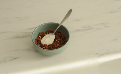 Granola with yogurt in a plate on the kitchen marble table, the concept of a healthy breakfast, front view