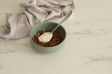 Granola with yogurt in a plate on the kitchen marble table, the concept of a healthy breakfast, front view