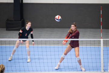 Female college volleyball player passing the ball while the libero watches