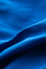 Royal blue fabric waves across the frame, creating an elegant, minimalist design with light and shadow interplay.