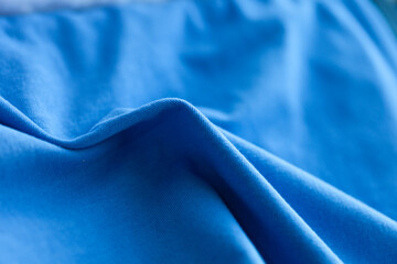 The soft folds of vibrant blue fabric create a visually appealing texture, adding depth and...