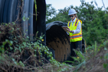 Construction surveyor or engineer working inspection damaged black corrugated pipe and construction...