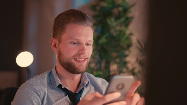 Businessman Sitting at Computer and Checking Smartphone