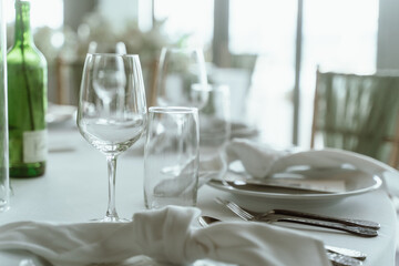 Wedding. Banquet. The chairs and round table for guests, served with cutlery, flowers and crockery and covered with a tablecloth,  green and white theme.