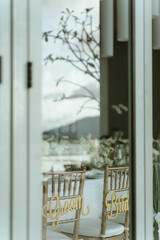 Wedding. Banquet. The chairs and round table for guests, served with cutlery, flowers and crockery and covered with a tablecloth,  green and white theme.