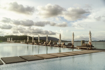 View of the swimming pool on the rooftop of a luxury hotel in the evening, with sunshades and loungers, evening light.