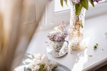 A lilac bouquet elegantly arranged in a porcelain teacup, with vibrant purple and white blossoms creating a cozy and refined setting. Perfect for themes of spring decor and natural beauty.