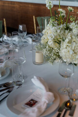 Wedding. Banquet. The chairs and round table for guests, served with cutlery, flowers and crockery and covered with a tablecloth,  green and white theme.
