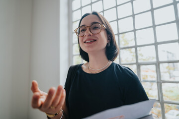 A confident professor engages with students in a bright, modern setting. She appears enthusiastic...