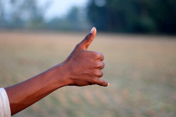 A hand clenched into a fist with one of its thumbs raised.
