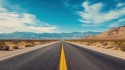Naklejka premium Scenic road through a vast desert landscape leading towards distant mountains