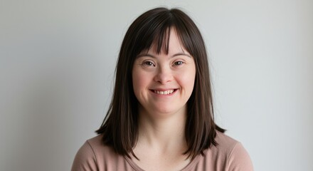 Fototapeta premium Young woman with Down syndrome smiling against a neutral background 