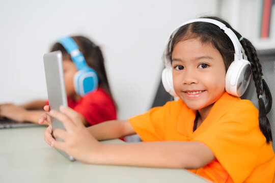 Two young asian students using laptop and tablet for online education