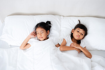 Two asian children sleeping peacefully in white bed holding hands