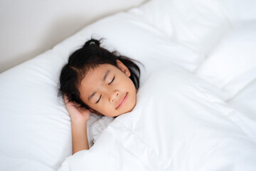 Little girl sleeping peacefully in white bedding