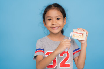 Little girl learning proper tooth brushing technique with model jaw