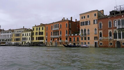 Gondola navigating grand canal past colorful venetian buildings. Action