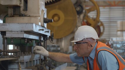 Engineer or operator wearing a safety suit working bending metal sheet by sheet press bending machine in workshop, Worker in factory at metal folding machine putting work piece at factory industry