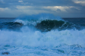 Stormy sea with big waves crashing onto the seashore with spray.