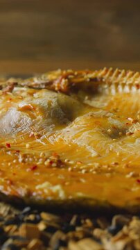 Tasty dressed ide fish with spicy seasonings and crust lies on pile of decayed wooden chips and charcoals in smokehouse close view slow motion
