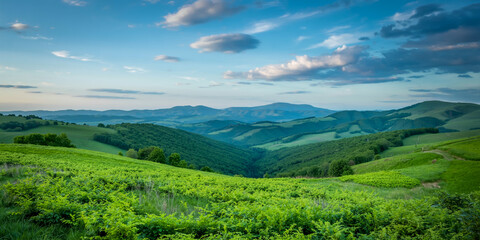Obraz premium Breathtaking panoramic landscape of rolling lime-green meadows, lush forested hills, and misty mountain ranges beneath a vibrant azure sky with wispy, dynamic cloud patterns