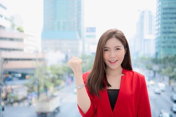 A confident businesswoman celebrates success against a bustling city backdrop, radiating positivity and ambition.