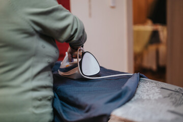Senior woman ironing a piece of fabric on an ironing board, showcasing a daily household task in a...