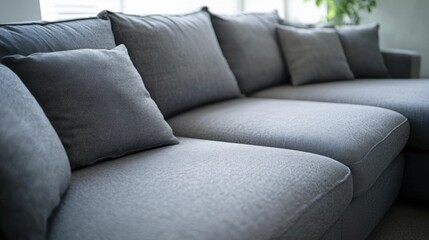 The image showcases a contemporary living room setting with a gray sectional sofa featuring geometric patterns on the throw pillows and a smooth, curved backrest. The sofa is set against a