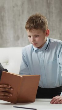 Skilled African-American teacher shows exercise in textbook to junior student at private English language tuition with native speaker slow motion