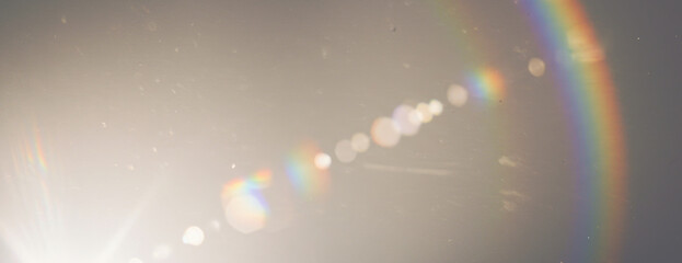 A strong lens flare with prominent curved rainbow refraction, scattering luminous effect on transparent background
