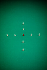 Red pawn amid white pawns on grass