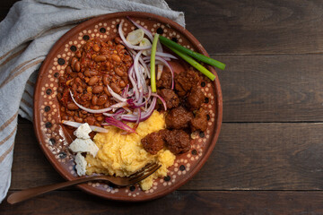 Traditional Eastern European corn mush, beans and vegan seitan meat on clay plate