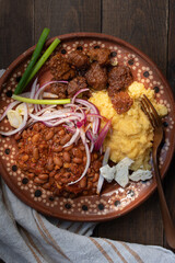 Traditional Eastern European corn mush, beans and vegan seitan meat on clay plate