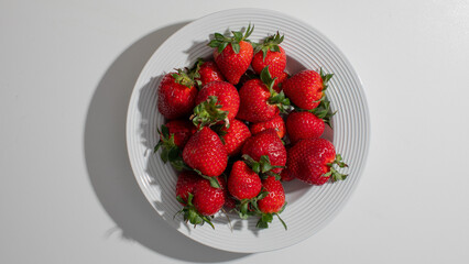 Fresh strawberries on a white plate, vibrant summer fruit, ideal for picnics and healthy eating during Independence Day