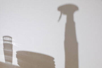 Shadow of a spray bottle on wall, minimalistic home cleaning concept, bright hygiene, spring cleaning inspiration