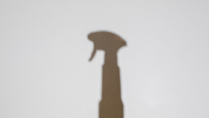 Shadow of spray bottle on white wall, minimalist cleaning concept, household chores, spring...