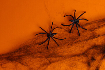 Black decorative web with spiders on orange background. Halloween decor. Copy space