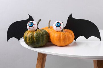 Halloween pumpkin with googly eyes and bat wings on table