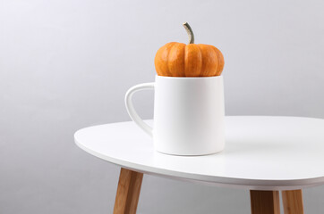 White ceramic cup mockup on table with pumpkin