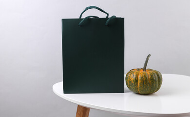 Green cardboard bag and pumpkin on the table. Autumn discounts