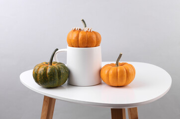 White ceramic cup mockup on table with pumpkins