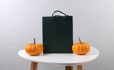 Green cardboard bag and pumpkins on the table. Autumn discounts