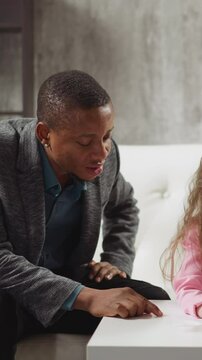 Young black English teacher writes invisible letters by finger on table and little kids guess and write at home lesson with native speaker slow motion