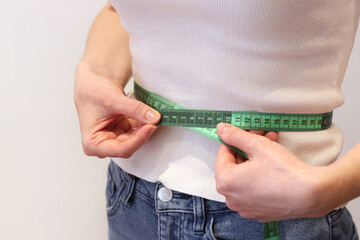 Girl measures her waist with a tape measure. Girl with a tape measure in her hands. Concept of...