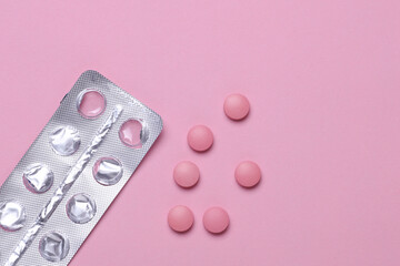 Pink pills with blister on pastel background. Medicine concept