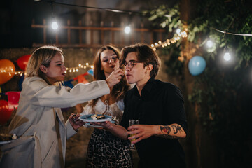 A group of friends sharing food and joy in a warmly lit backyard party with festive decorations. Celebratory atmosphere emphasizing friendship and happiness on a special birthday occasion.