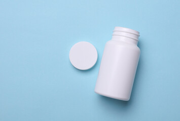 White plastic pill bottle on blue background. Mockup for design