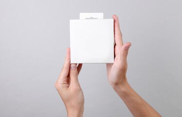 Female hands holding white blank box on gray background