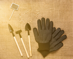 Set of miniature gardening tools with a chalkboard and worlking gloves on burlap