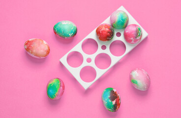 Colored Easter eggs in tray on pink background.
